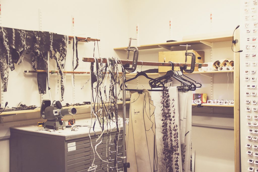 Paper textile project workspace with hangers and a projector and architectural textile paper creations 