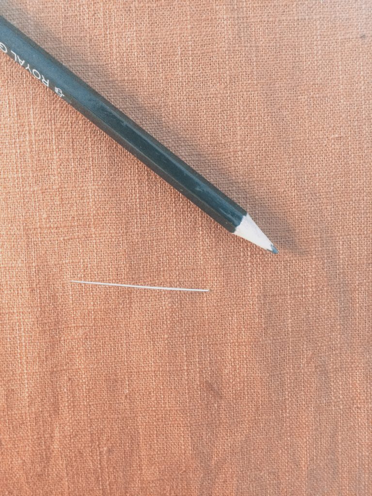 orange brown linen with needle and pencil to mark dart point