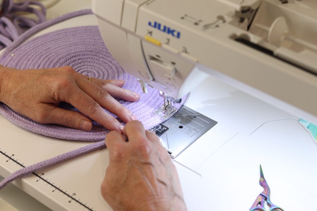 stitching a light purple rope bag